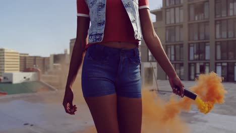 Fashionable-young-woman-on-urban-rooftop-using-a-smoke-grenade