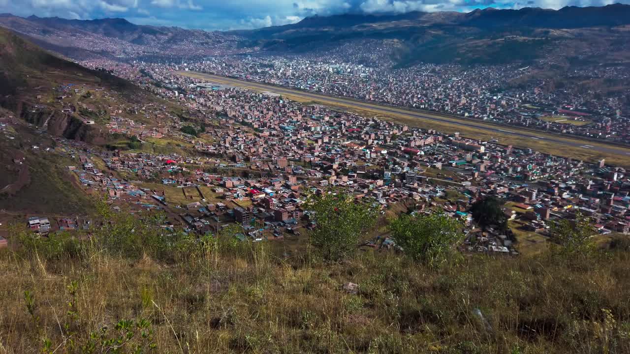 Cusco airport runways seen from mountain slopes overlooking the city. San Jeronimo mountain slopes with native vegetation. Tilt up reveal shot