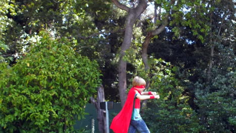 Wow and Pow text against boy in superhero costume running in the garden