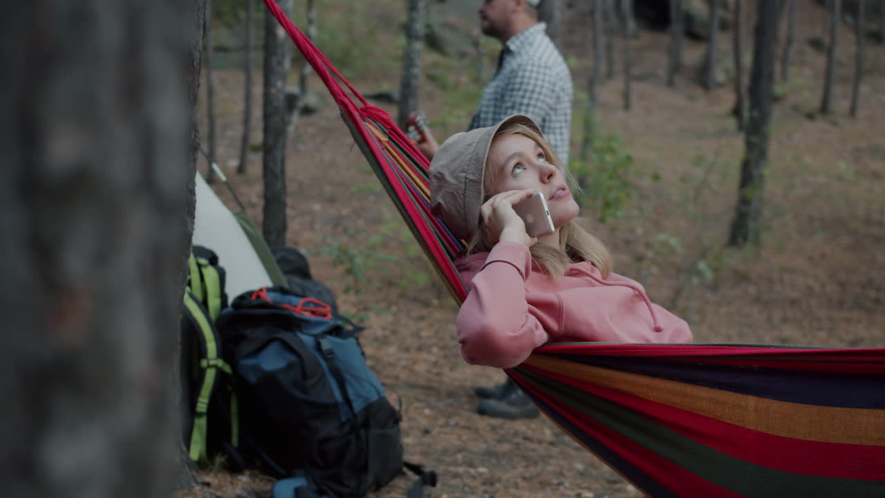 Woman on a hammock enjoying a phone call in the forest