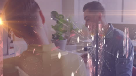 at desk, two people working with fireworks animation overlaid on screen