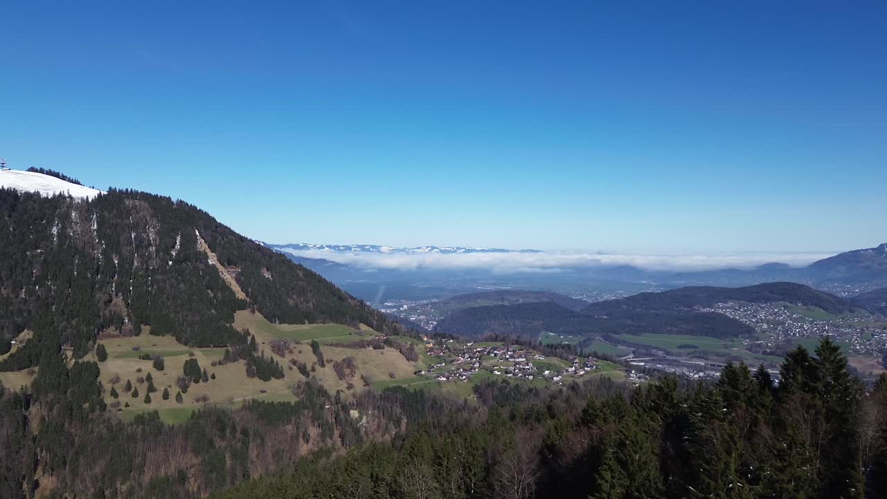 un avión no tripulado vuela entre pinos revelando un hermoso paisaje urbano de montaña en vorarlberg, austria