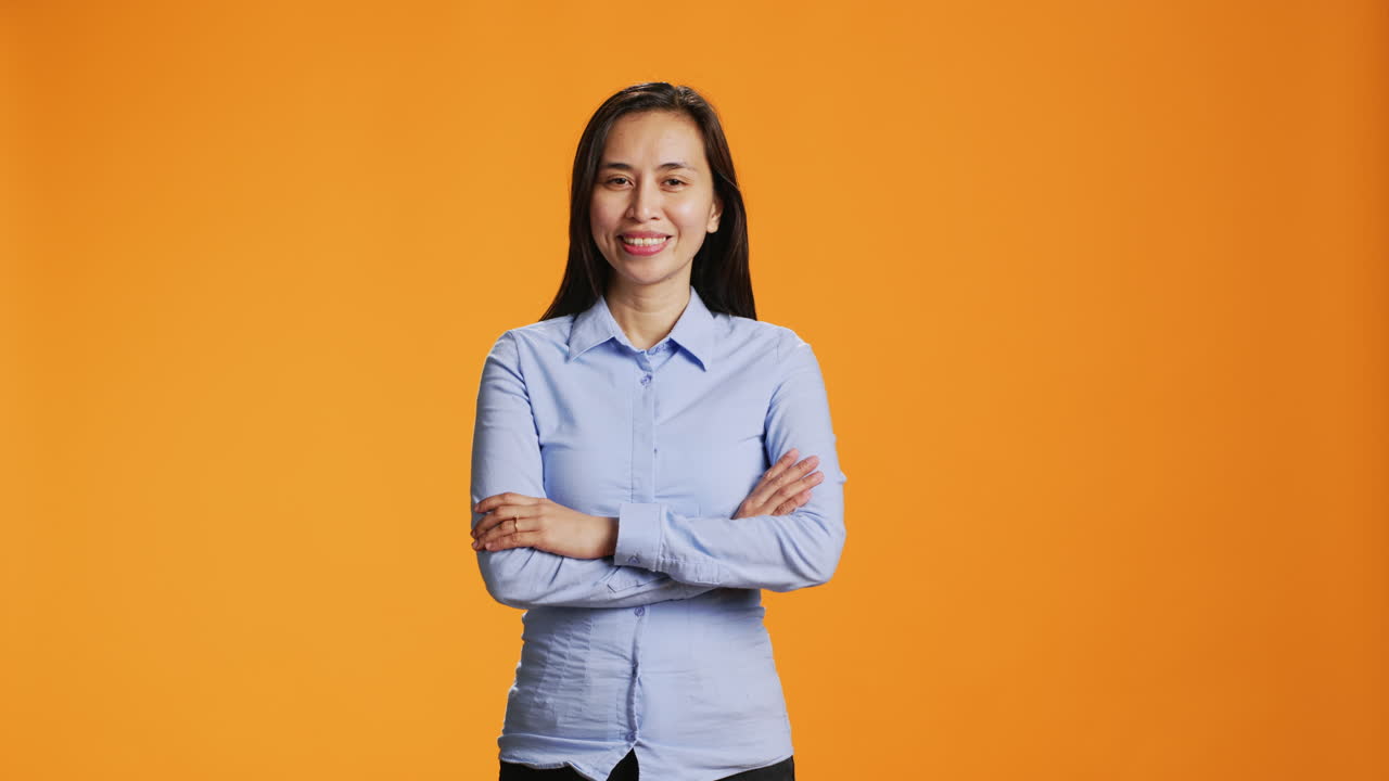 Happy woman poses with arms crossed in studio