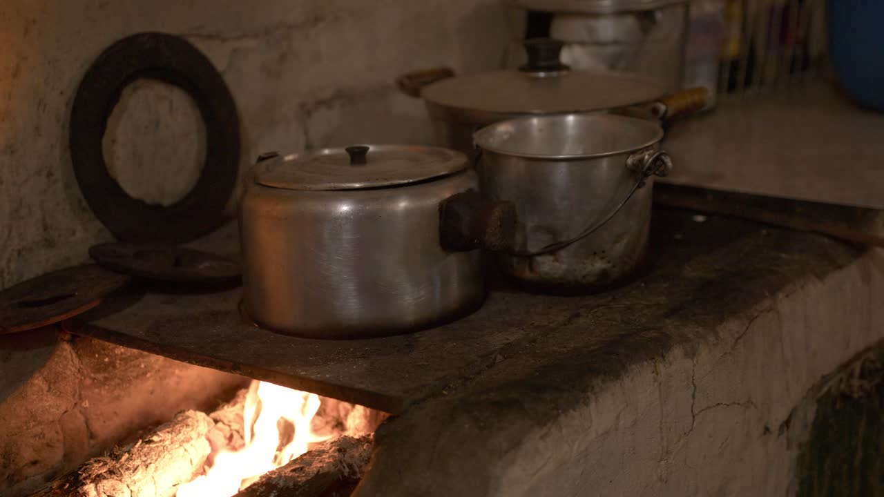 una antigua cocina tradicional paraguaya con fuego intenso y madera, con dos ollas fumando y hirviendo intensamente con comida dentro