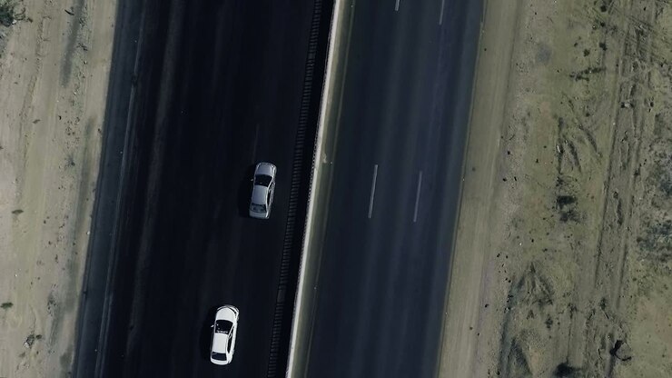 Una ripresa aerea dall'alto al rallentatore di due auto in movimento su un'autostrada nelle aree settentrionali.