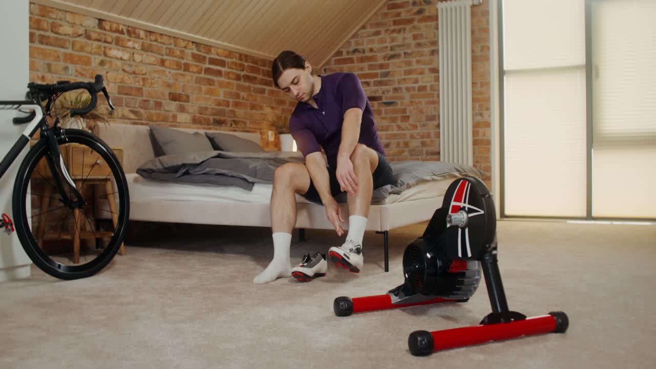 hombre preparándose para un entrenamiento de ciclismo en su dormitorio.