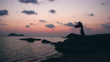 silhouette of of sexy, elegant and erotic arabian woman performing belly dance on the beach during golden hour. static.