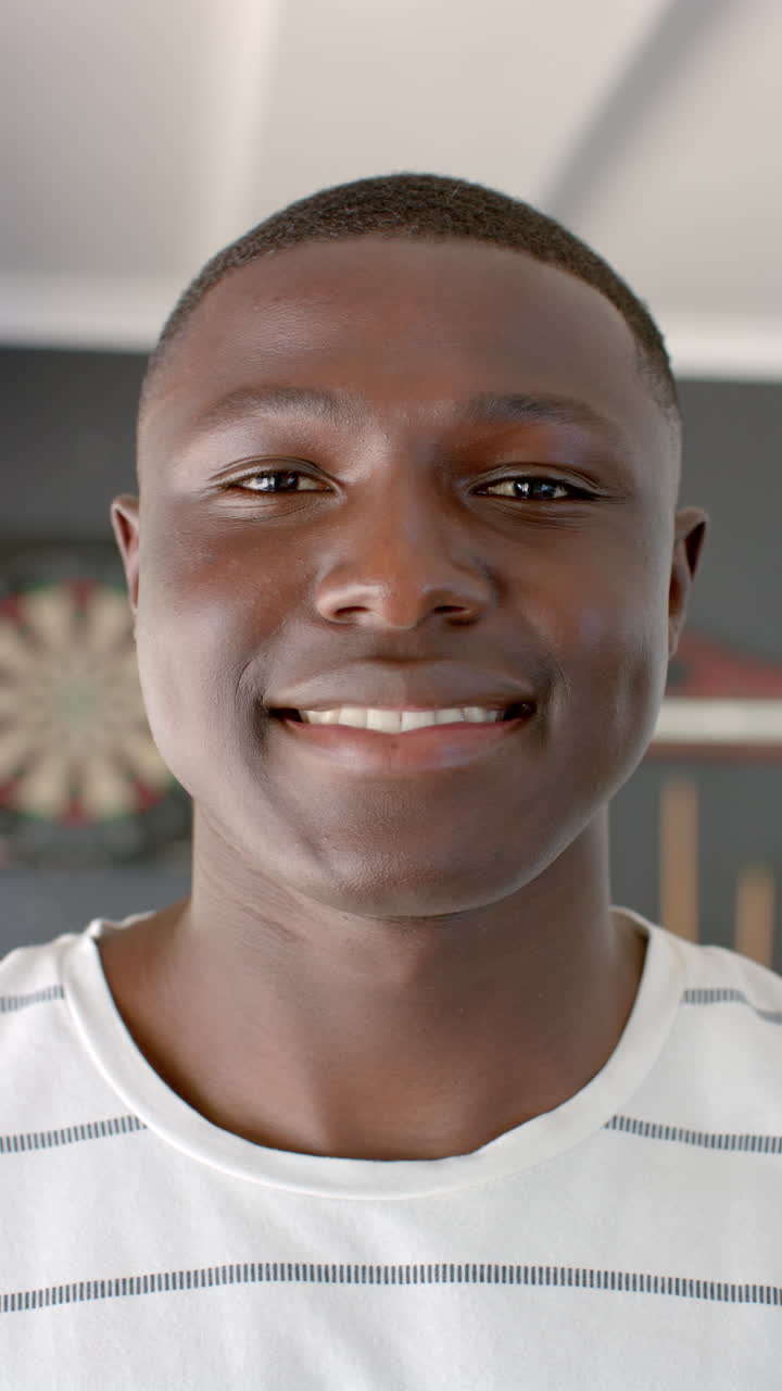 Vertical video: A young African American man smiles warmly, gray background