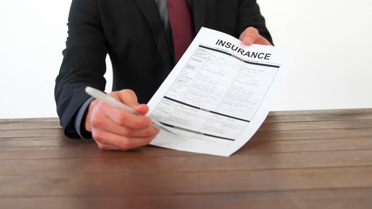 Businessman sitting at desk holding insurance contract