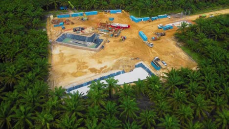 Cinematic-Drone-Footage-of-Onshore-Drilling-Rig-equipment-structure-for-oil-exploration-and-exploitation-in-the-middle-of-jungle-surrounded-by-palm-oil-trees-during-sunset-and-high-oil-price