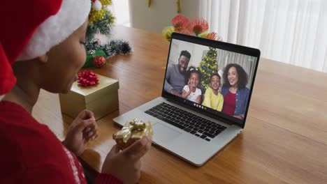 Afroamerikanische-Frau-Mit-Weihnachtsmütze-Nutzt-Laptop-Für-Weihnachtsvideoanruf-Mit-Der-Familie-Auf-Dem-Bildschirm