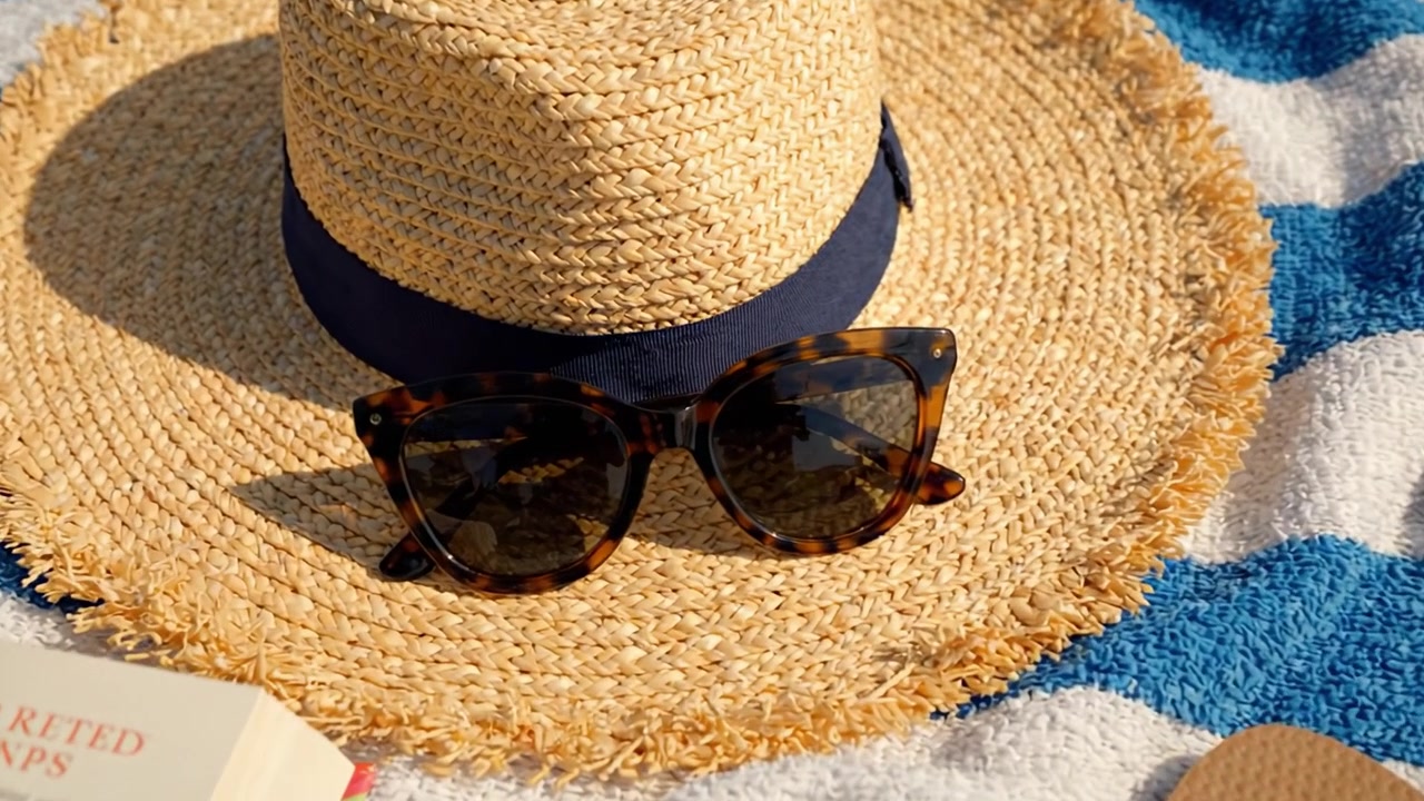 Een levendige zomerse setting met een stijlvolle strohoed, trendy zonnebril en ontspannende strandbenodigdheden, vastgelegd in een zonovergoten tafereel.