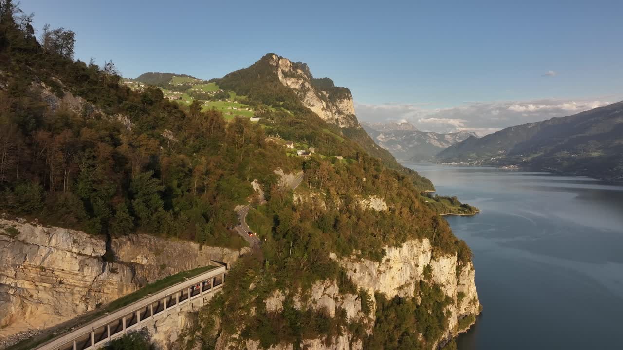 Welcome to the Swiss Alps. A road leading around a lake in the mountains and small villages in the hills. Aerial shot