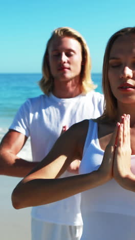 couple performing yoga at beach