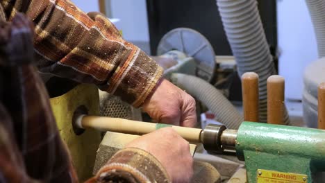 Sanding-wooden-dowel-rod-on-turning-wooden-lathe