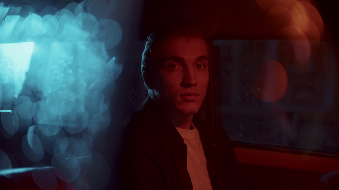Portrait of Young Handsome Man in Car with Bokeh Reflections on Window Glass