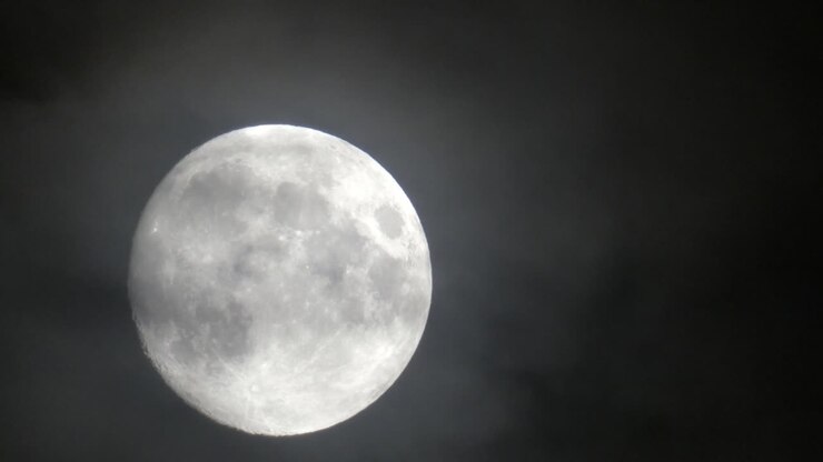 Lua cheia movendo-se da esquerda para a direita em uma noite nublada.
