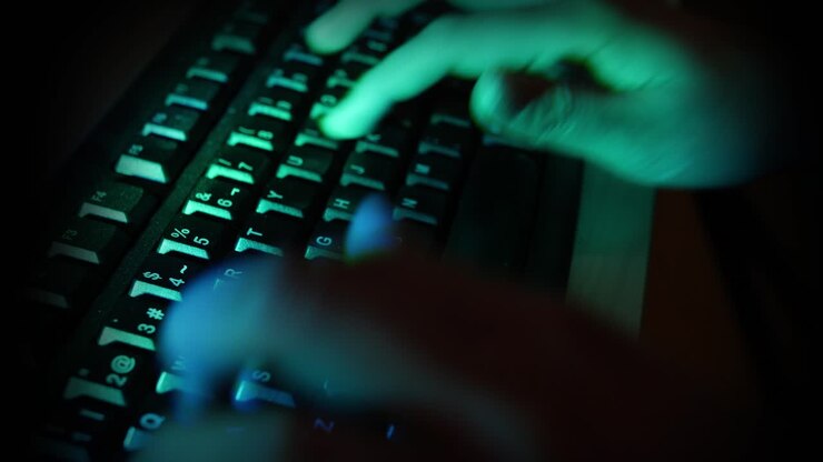 Nærbillede af hænder der taster på et computertastatur i mørke