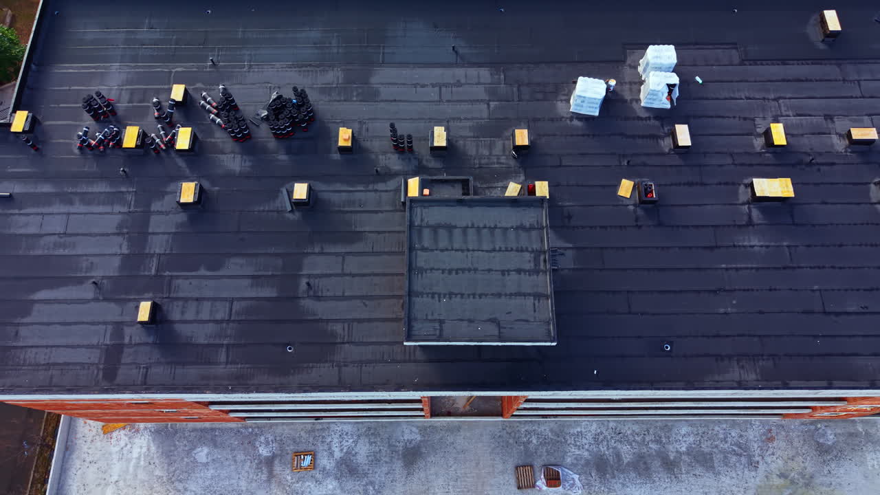 View of a rooftop construction site showing building materials and tools being arranged during mid-morning hours