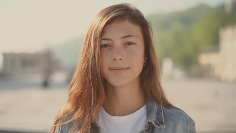 an smily pretty teenager girl looks directly into the camera