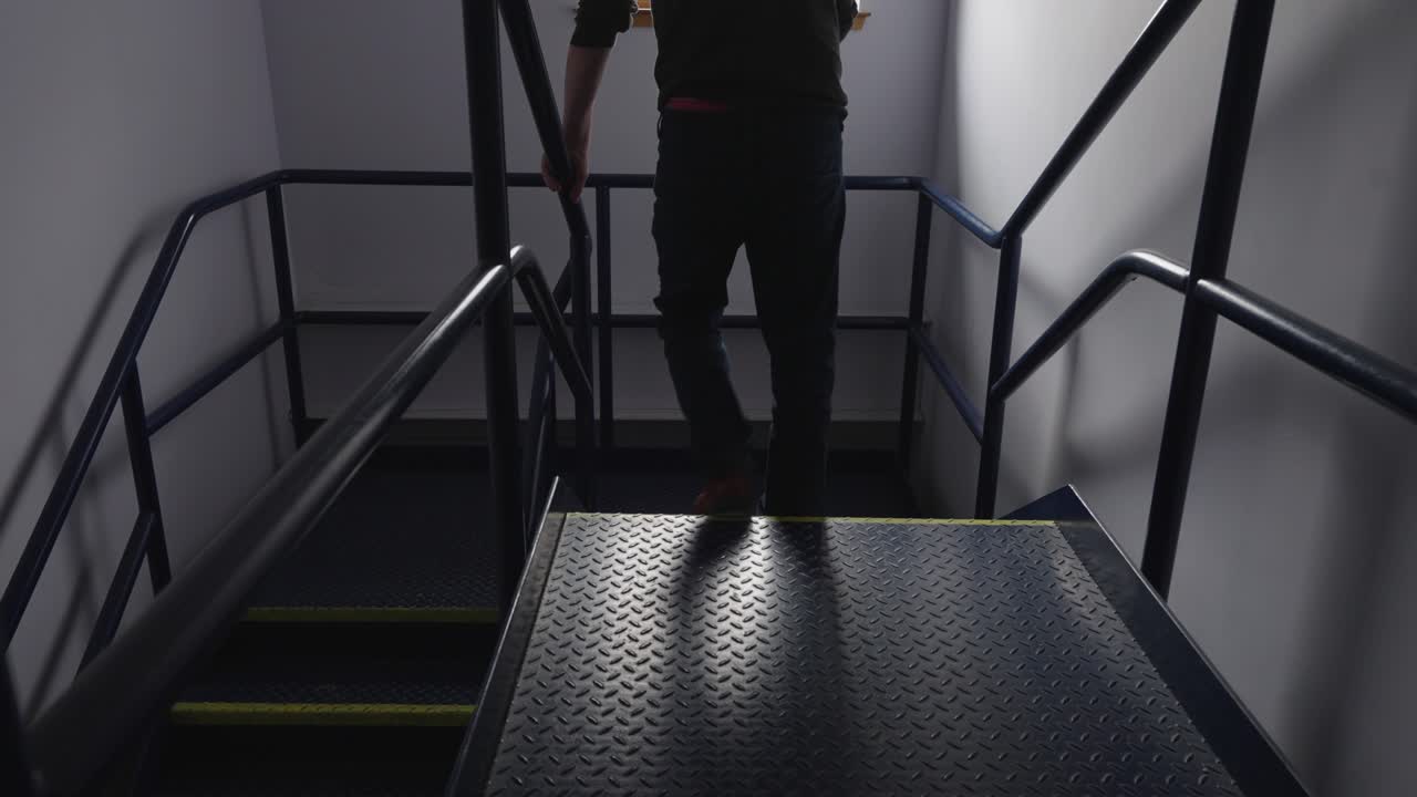 직장에서 한 남자가 어두운 계단을 내려가며 고통스러워서 레일링에 부혔습니다.