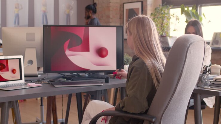 Diseñadora gráfica mirando a la cámara mientras está sentada en una silla de oficina en un estudio de animación 1