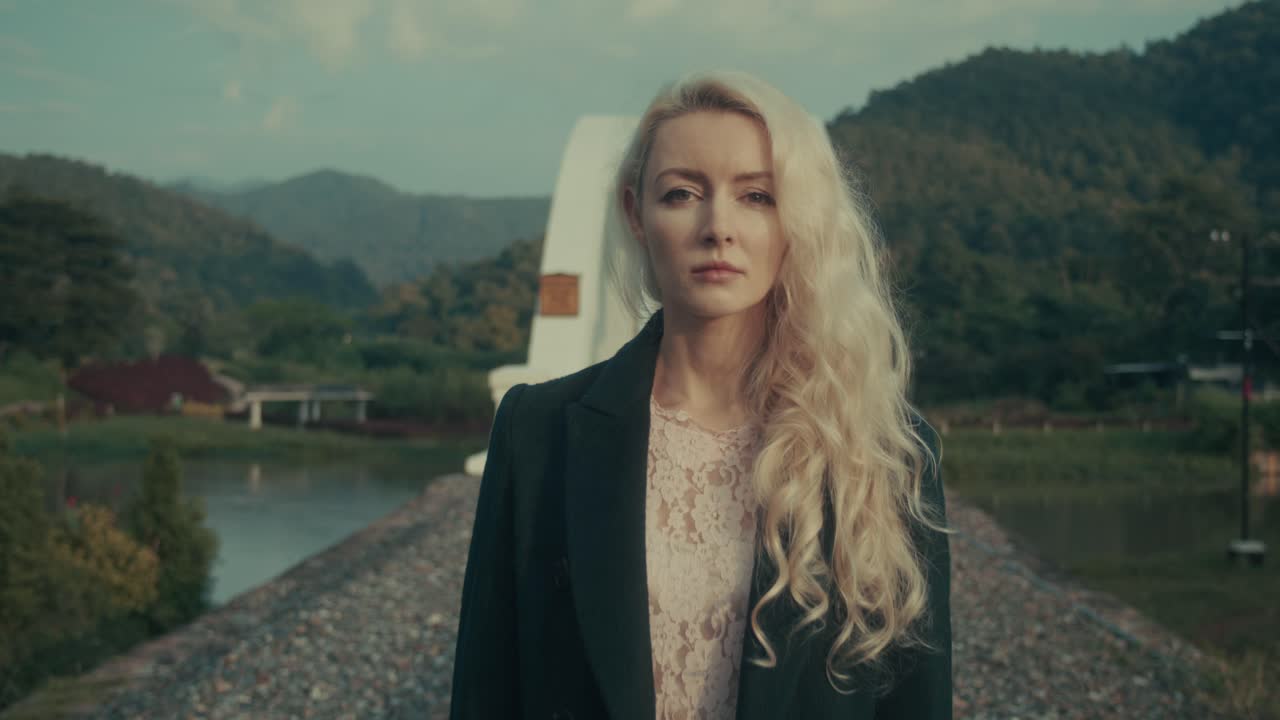 Woman walking on a bridge over a river, mountains in the background
