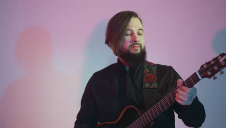 bearded guitarist in a black shirt passionately playing a red guitar, subtly moving his head against a white background with a soft pink and blue light gradient