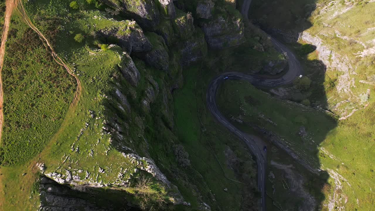 Top-down aerial shot of a blue car navigating a winding road through Cheddar Gorge.