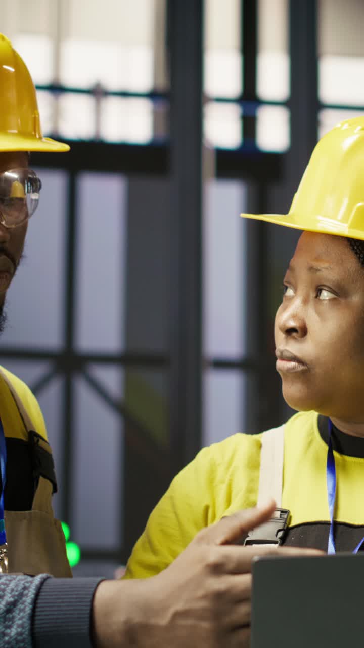 Vertical video Smart factory engineering team using laptop to calibrate high tech machinery