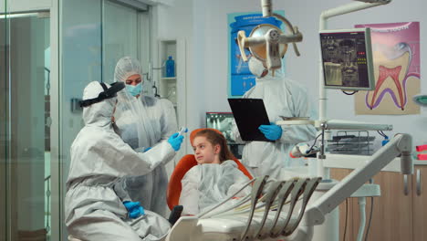 stomatologist with face shield measuring girl temperature