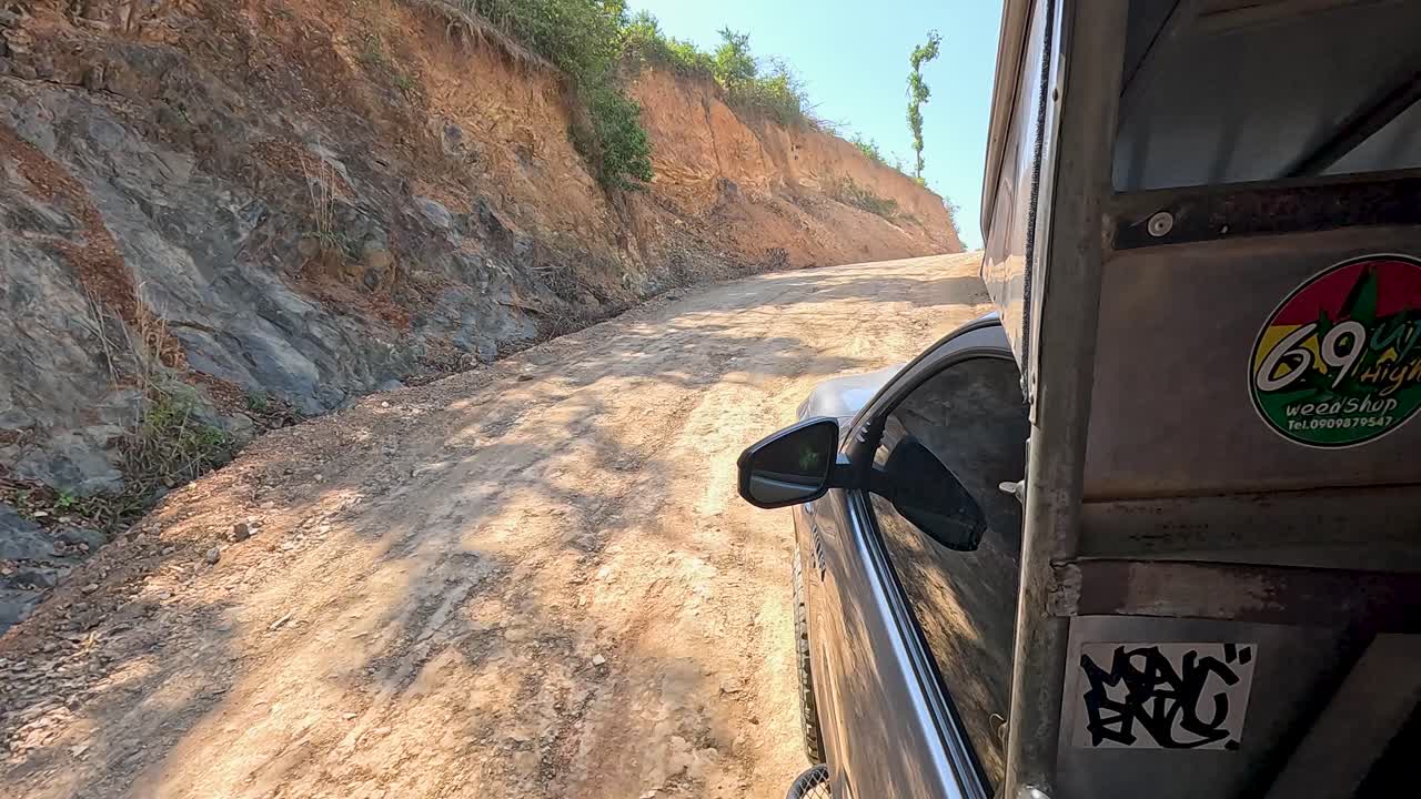 A vehicle navigates a rugged dirt road in Phuket, Thailand, under bright daylight, capturing the essence of adventure travel
