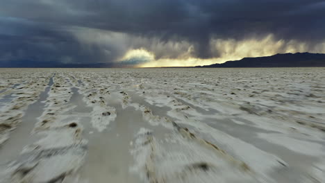 dynamic low flying above salt flats, bonneville, utah, usa, dramatic stormy sky on endless horizon, tilt up drone shot