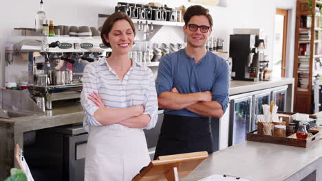 young coffee shop owners behind counter with arms crossed