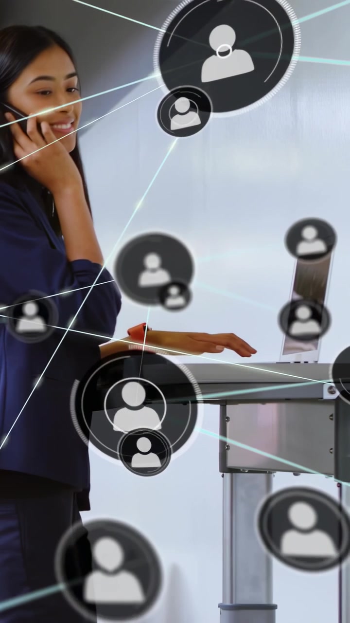 Vertical video: Woman walking to desk typing laptop and calling while network growing showing links