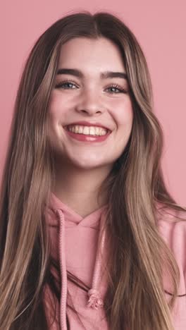 cheerful young woman smiling against pink wall
