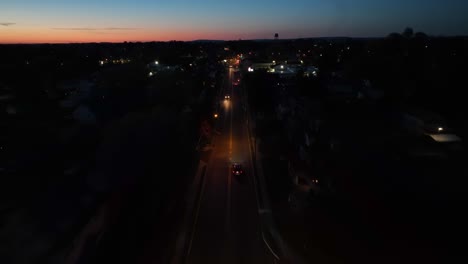 Drone-Sobrevuela-Una-Calle-Oscura-Con-Tráfico-Después-Del-Atardecer-En-Una-Ciudad-Americana