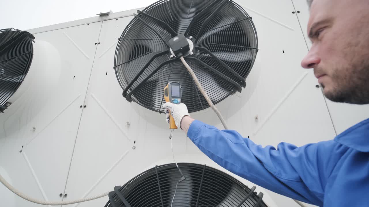 Technician uses a thermal imaging infrared thermometer to check the condensing unit heat exchanger