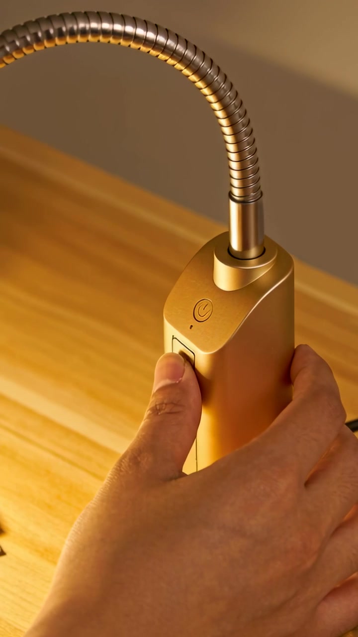 Video verticale: Una mano entra e afferra una lampada d'oro a casa, premendo l'interruttore anteriore per accenderla.