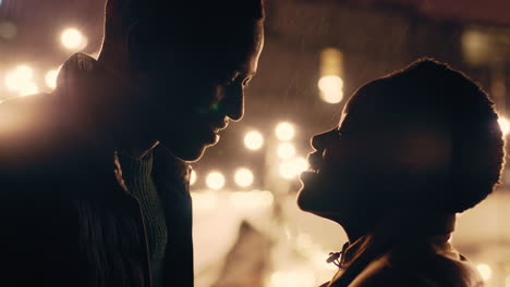 young-african-american-couple-kissing-in-rain-holding-hands-enjoying-romantic-connection-on-beautiful-rooftop-at-night