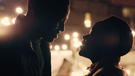 young african american couple kissing in rain holding hands enjoying romantic connection on beautiful rooftop at night