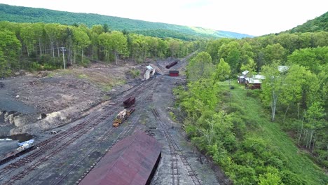 an aerial view of an abandoned narrow gauge coal rail road with rusting hoppers and freight cars and support building starting to be restored