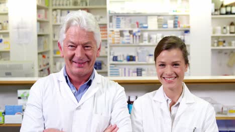 smiling pharmacists standing with arms crossed in pharmacy