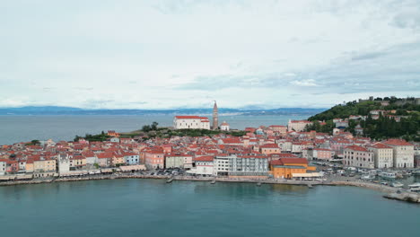 Imágenes-De-Un-Dron-De-Un-Vuelo-Sobre-El-Hermoso-Casco-Antiguo-De-Piran,-Eslovenia,-Con-Las-Colinas-Italianas-Al-Fondo