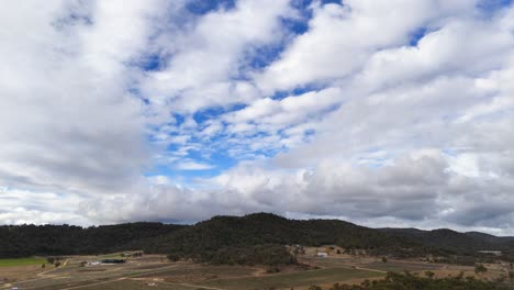 expansive sky with clouds above hills and farmland