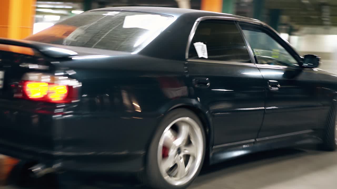 검은 차의 둥근 모션 커플이 주차장에서 나갑니다.