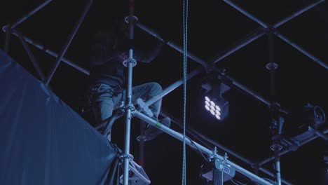 técnico de escenario trabajando en andamios por la noche