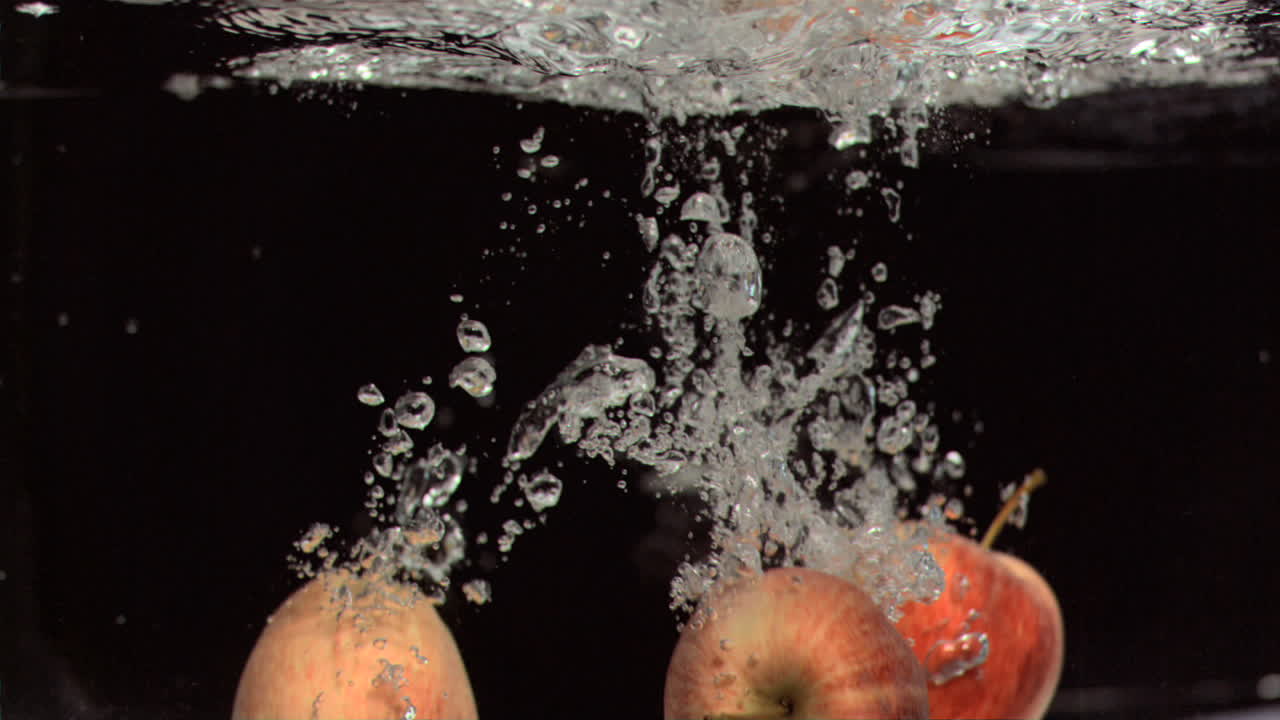 manzanas cayendo en el agua en súper cámara lenta