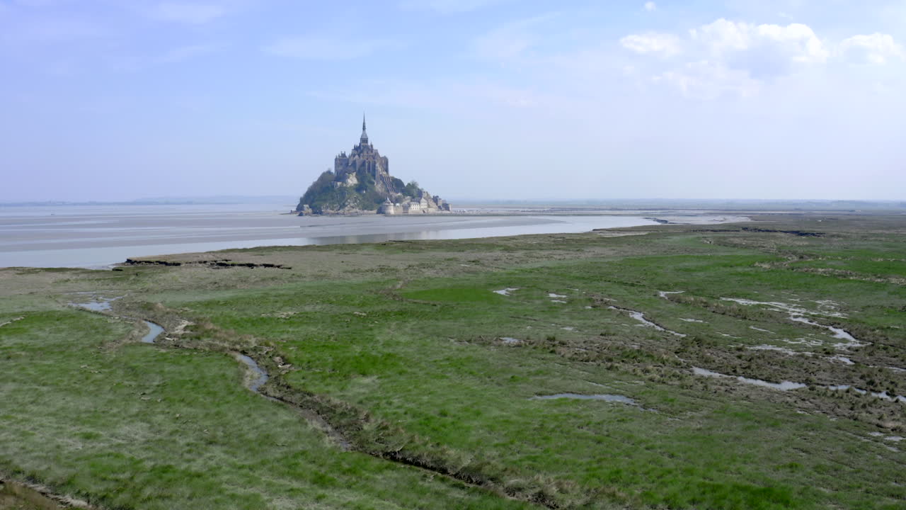un largo movimiento de paralaje del mont saint-michel siguiendo la línea de la costa y cerrándose por la entrada