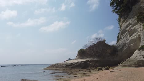una costa espectacular con acantilados calcáreos pálidos en una playa desierta con cielo azul y nubes al sol de la tarde